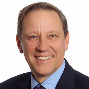 Ein lächelnder Mann im Anzug posiert für ein professionelles Porträt, ideal für geschäftliche Profile und Unternehmenswebsites.