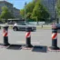 Neue Absperrungen mit rot-weißen Markierungen auf einer Stadtstraße, um die Verkehrssicherheit zu erhöhen und Fußgänger zu schützen.